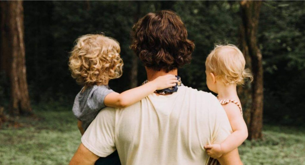 Miles and his two children from the back looking into a forest